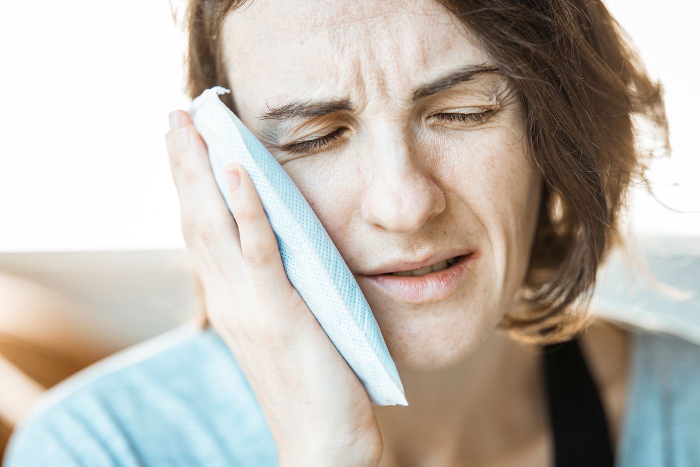 Woman with toothache holding an ice pack to her cheek
